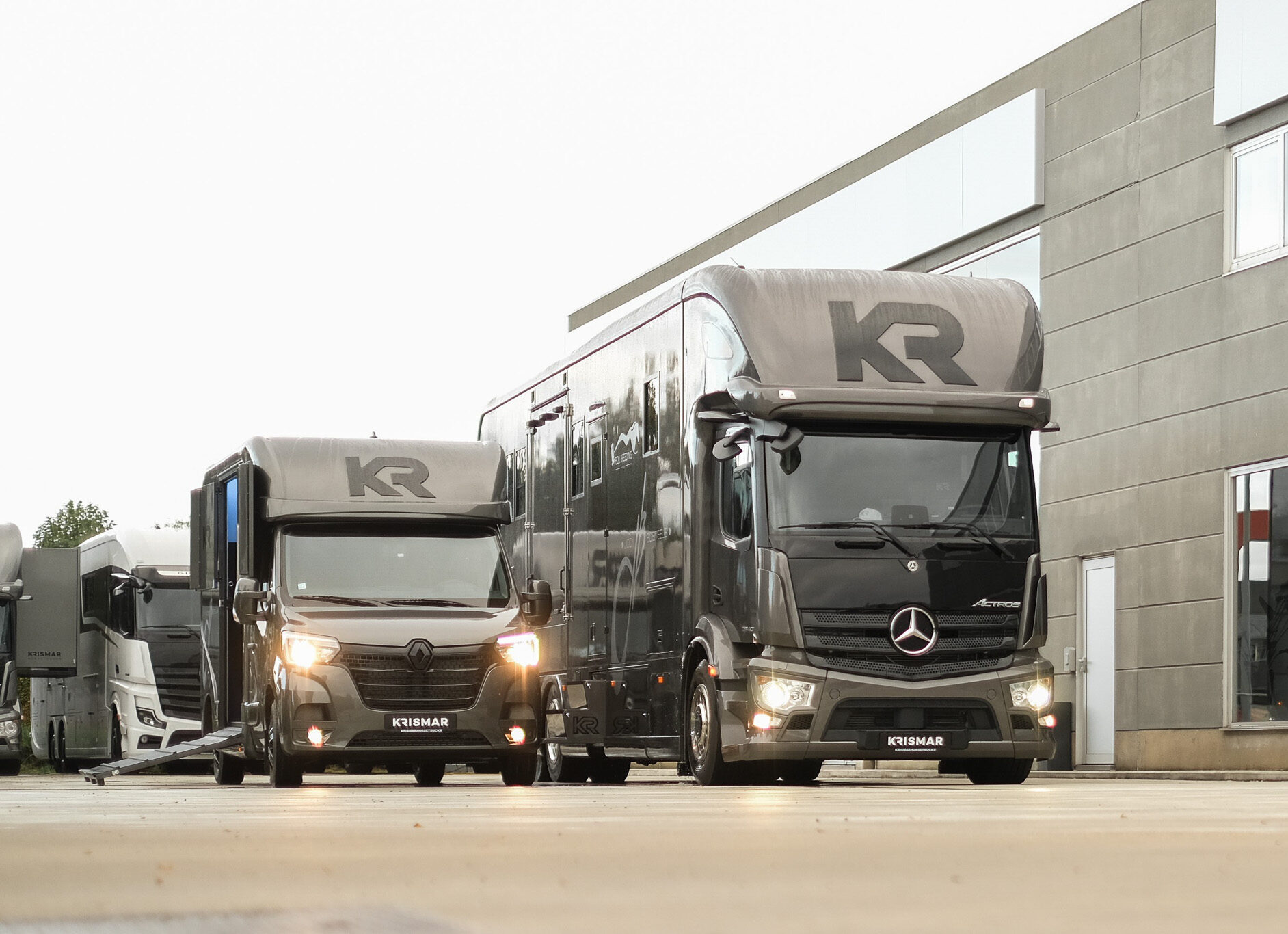 A gray Krismar horse truck parked next to a matching gray Krismar2-horse van.