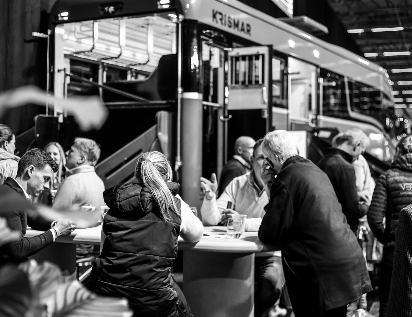 Visitors in conversation at the Krismar Horse Trucks stand, with a premium horse truck in the background.
